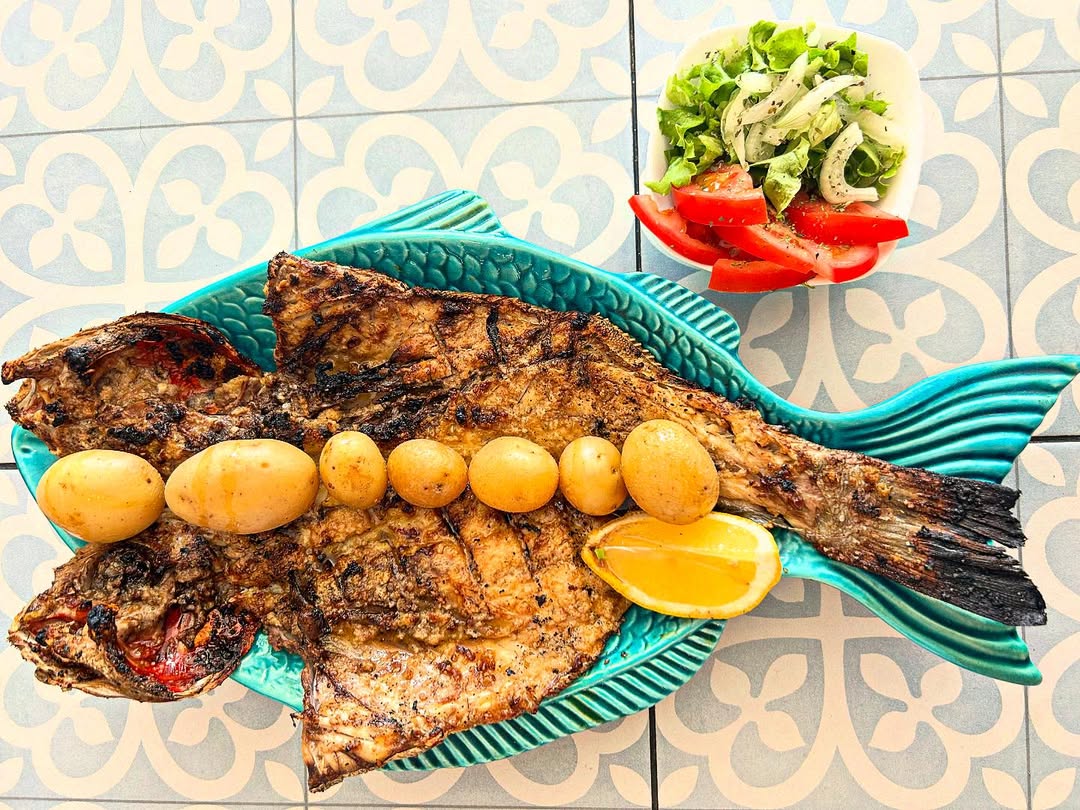 Peixe grelhado com batata cozida e rodelas de limão, sobre azulejos